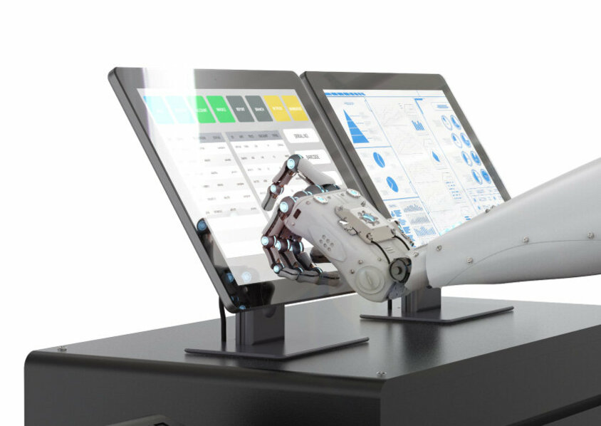 Ein Roboterarm tippt auf einen der zwei Bildschirme, die Produktionsdaten anzeigen