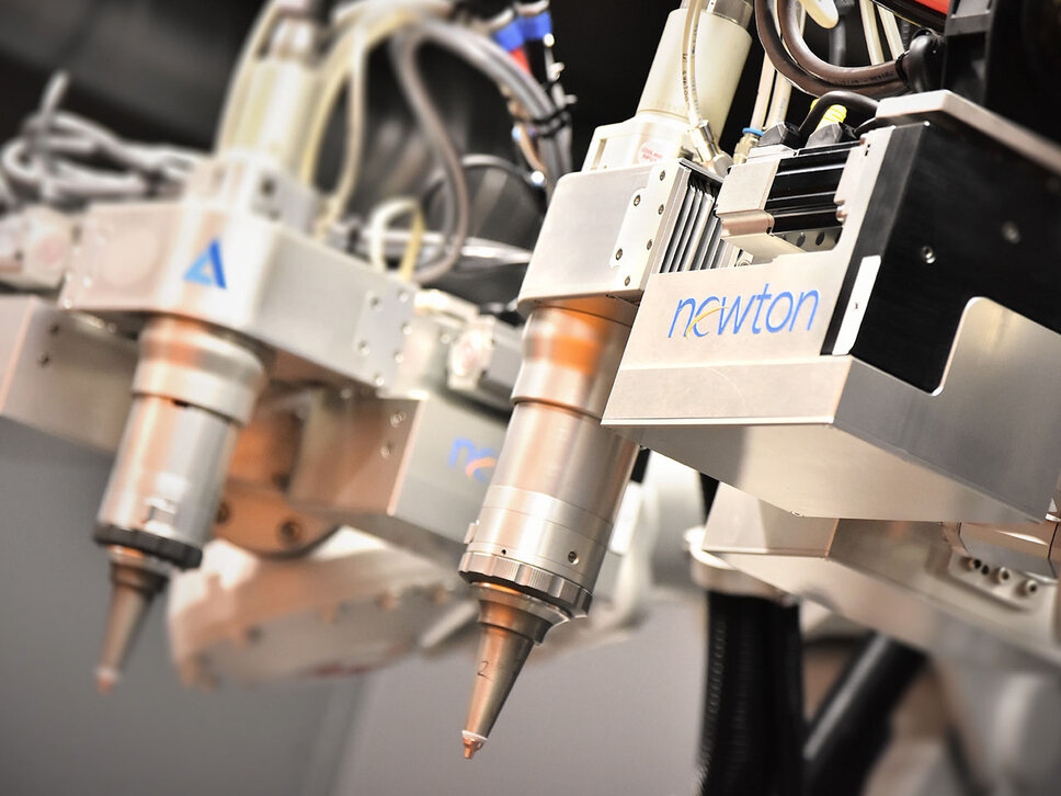 Detailaufnahme von zwei Newton-Schneidköpfen eines Roboterlasers, die präzise konstruiert und montiert sind, mit sichtbaren mechanischen Details und der komplexen Struktur der Schneidtechnologie.