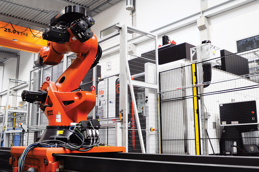Bild eines Transferroboters beim Rüsten von Werkstücken in ein Bearbeitungszentrum. Der Roboterarm ist dabei zu sehen, wie er geschickt und präzise Werkstücke handhabt und in die Maschine einlegt, was die Automatisierung und Effizienz in modernen Fertigungsprozessen unterstreicht.